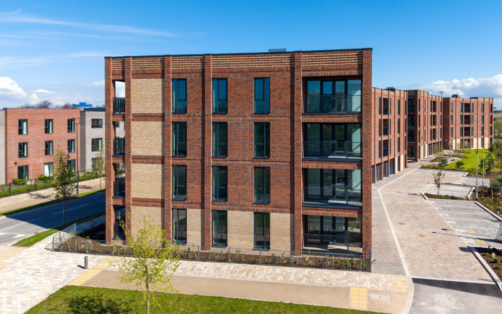 A facing view of the curved shape of the development showcasing the brickwork and balconies. 