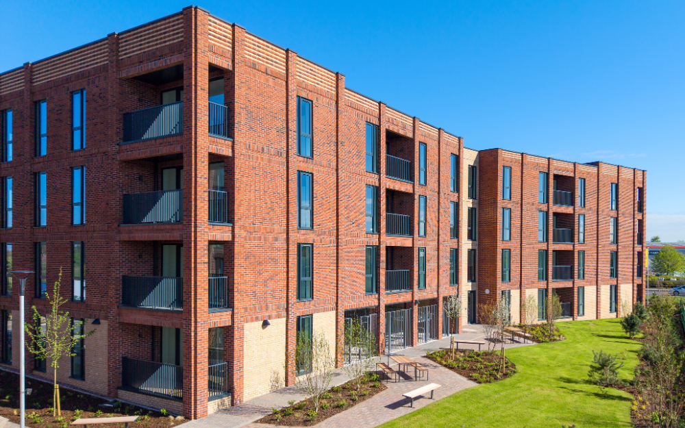 New affordable apartments with red brick, grey windows and balconies and landscaped gardens