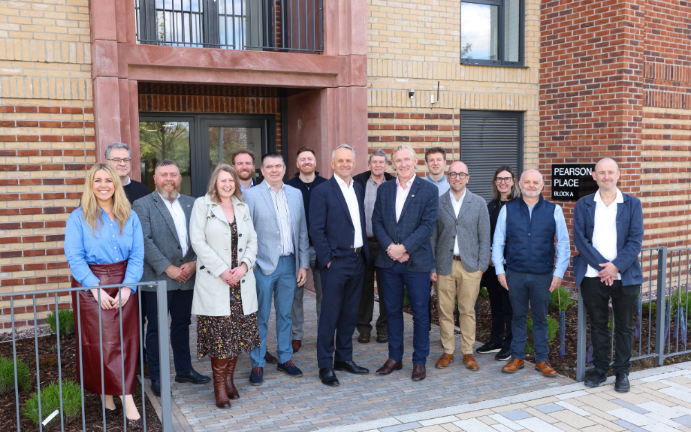 Team members gather in front of a recently completed new-build, affordable housing scheme, Pearson Place, within the Trafford Waters development